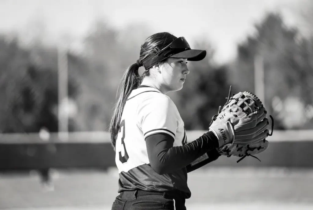 A softball player with softball gloves on the field